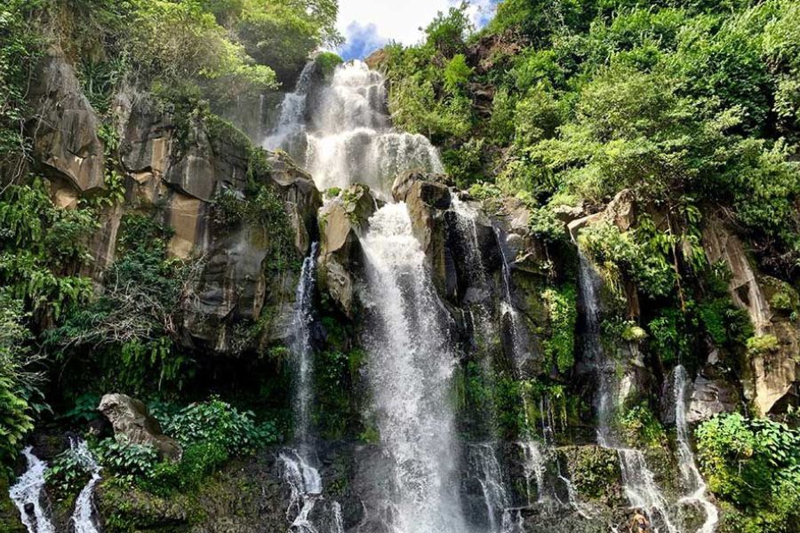 Multi-tiered waterfall cascading down a green, rocky cliff in Réunion Island