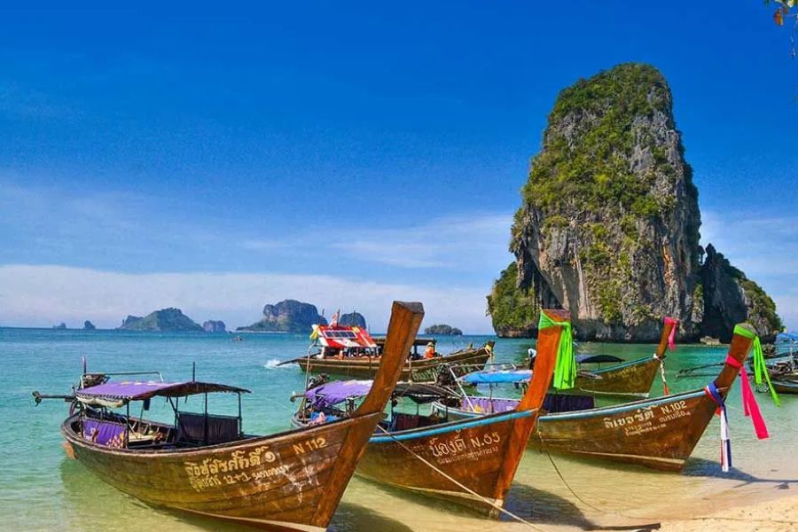 Longtail boats moored at Railay Beach, Krabi, with a limestone cliff behind