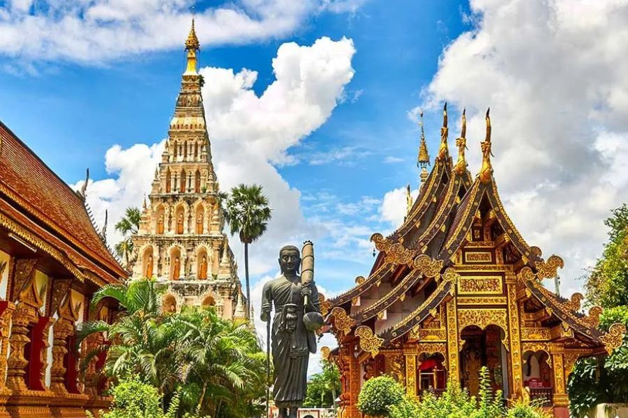 Golden Thai temple with an ornate spire and a standing Buddha statue