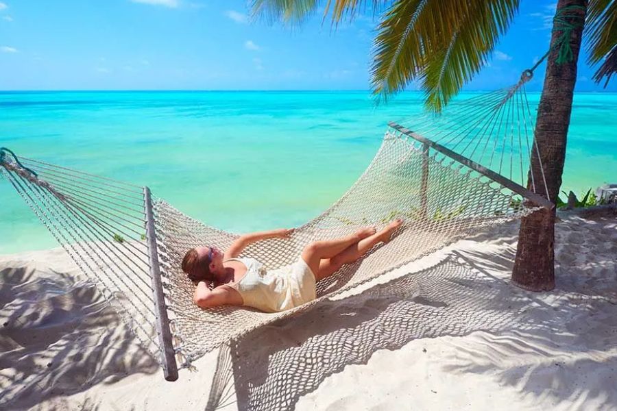 Relaxing in a hammock on a tropical beach with crystal-clear turquoise water.