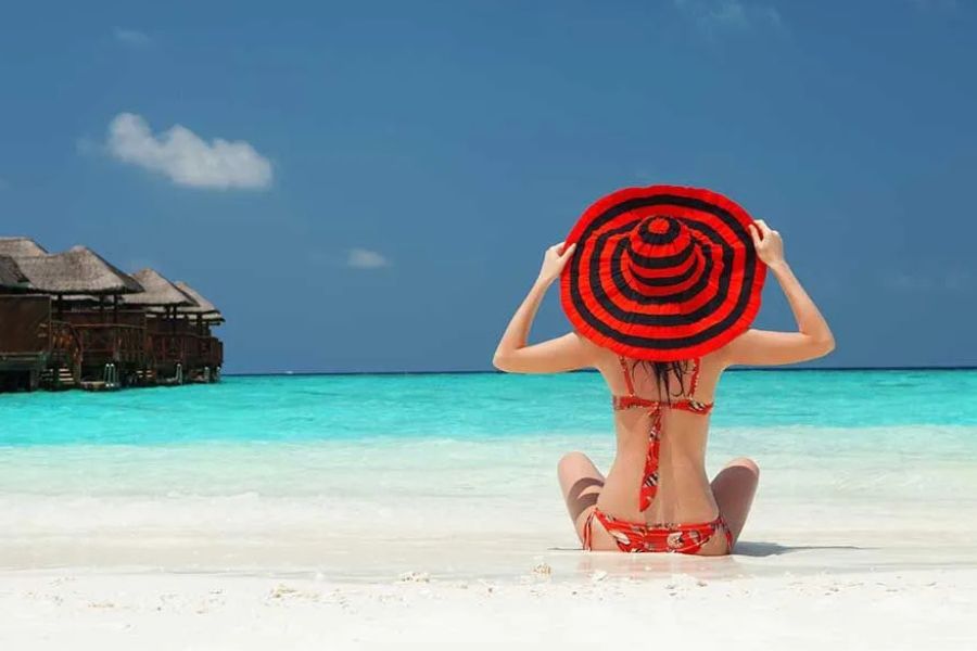 Woman enjoying a tropical Maldives beach beside an overwater resort