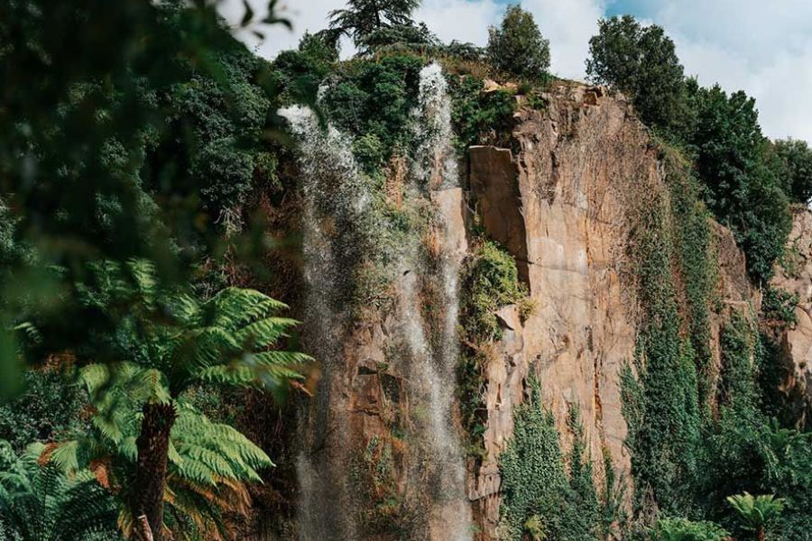 Tropical waterfall cascading down a lush volcanic cliff on Réunion Island.