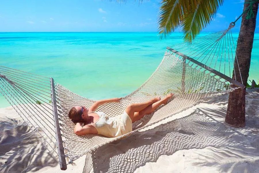 Woman relaxing in a hammock beside Zanzibar’s clear turquoise ocean.