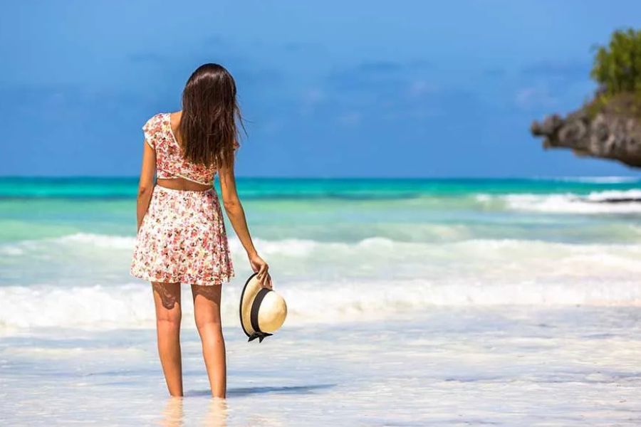 Woman enjoying the warm turquoise water on a beautiful Zanzibar beach.