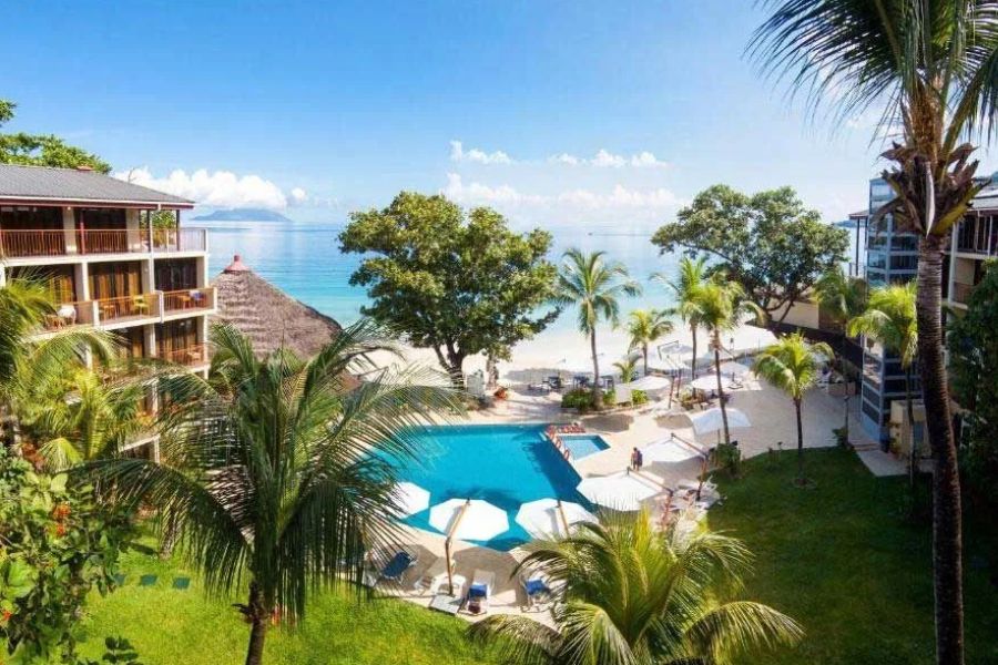 Tropical Seychelles resort with pool, palm trees and direct beach access.