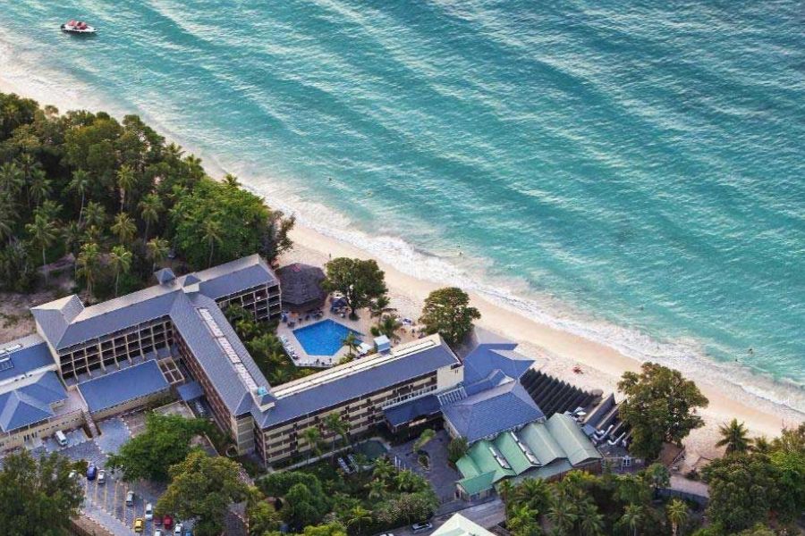 Aerial view of a beachfront resort beside turquoise waters in the Seychelles.