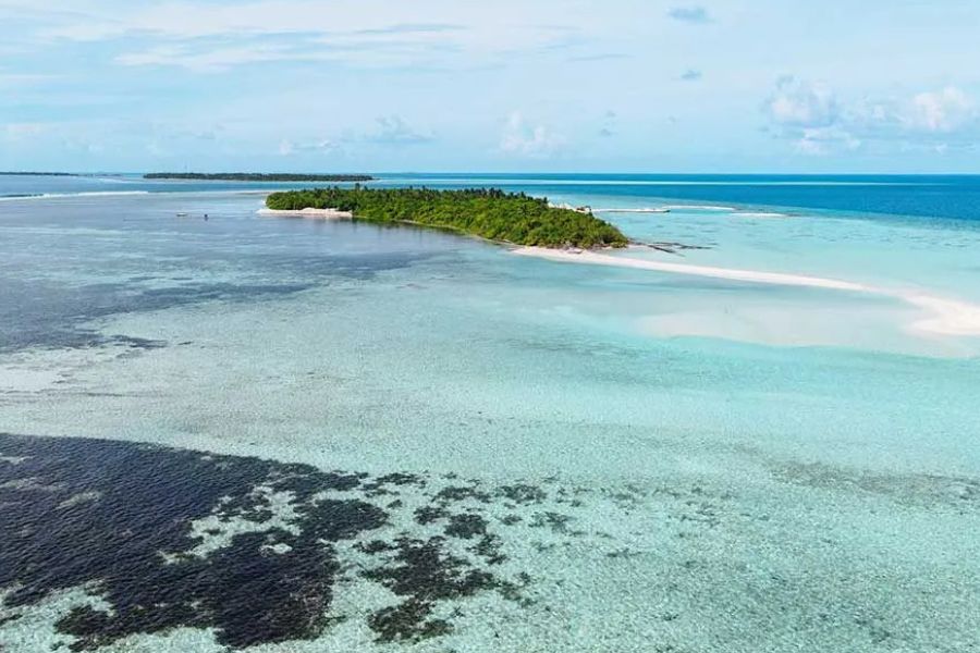 Aerial view of a remote Maldives island surrounded by a turquoise lagoon.