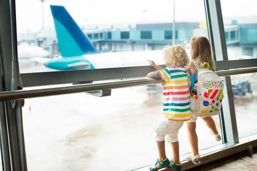 Children watching aircraft at the airport before their family holiday.
