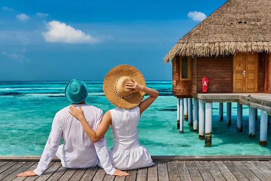 Couple relaxing beside an overwater villa in the Maldives.