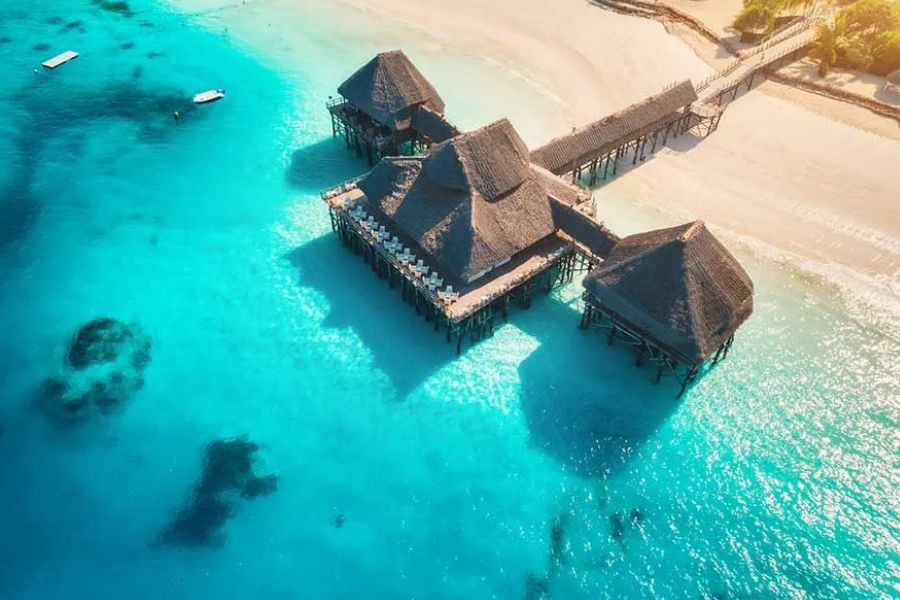 Aerial view of overwater villas above a turquoise lagoon in Zanzibar.