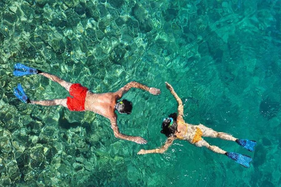 Couple snorkelling together in crystal-clear tropical waters.
