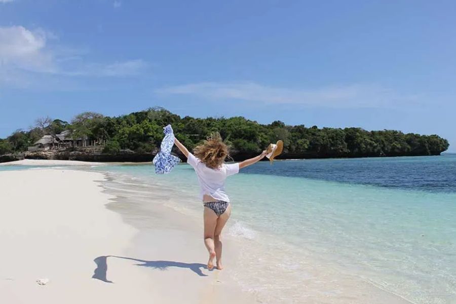 Woman enjoying a peaceful walk along a pristine Zanzibar beach.