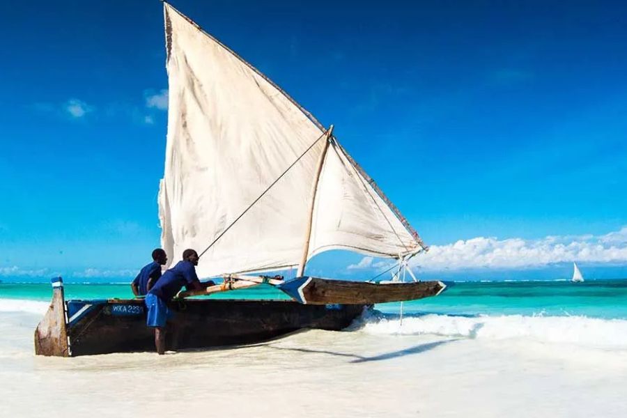 Traditional dhow sailing from a white-sand beach in Zanzibar.
