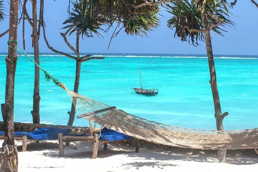 Hammock overlooking Zanzibar’s turquoise ocean and traditional dhow.