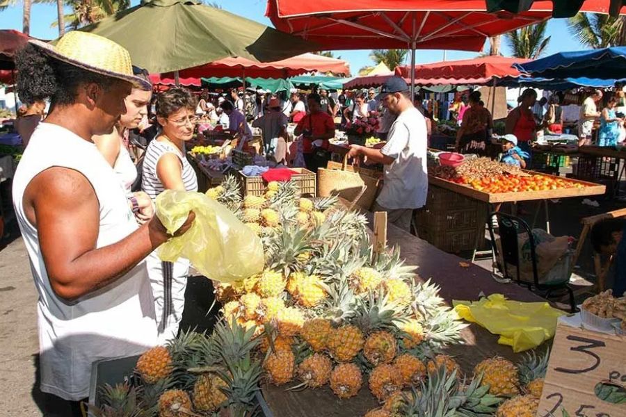 Colourful local market with fresh pineapples and produce on Réunion Island.
