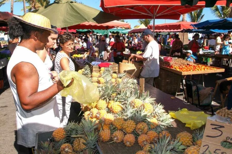 Colourful local market with fresh pineapples and produce on Réunion Island.
