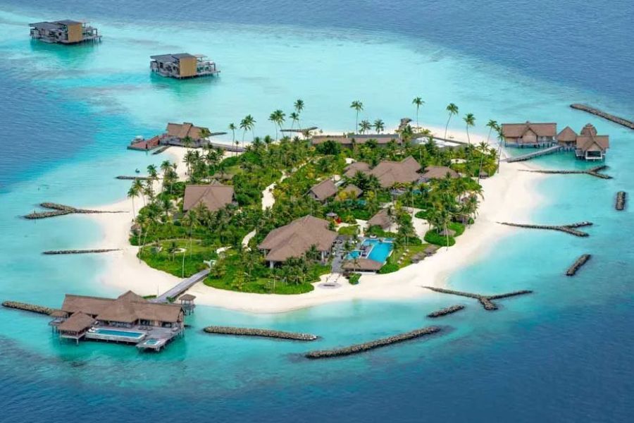 Private Maldives island resort surrounded by clear turquoise lagoon waters.