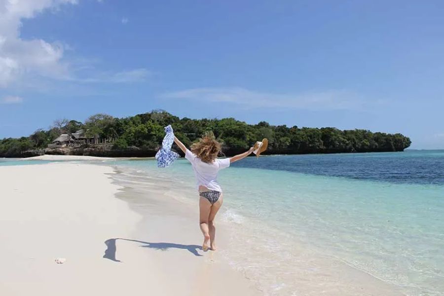 Woman enjoying a quiet walk along a pristine Zanzibar beach.