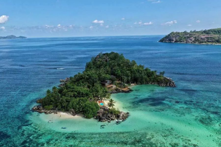 Aerial view of a small tropical island surrounded by clear turquoise ocean water