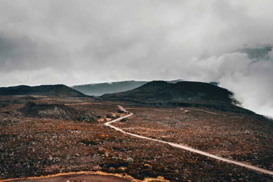 Winding road through a barren volcanic plateau with foggy mountains