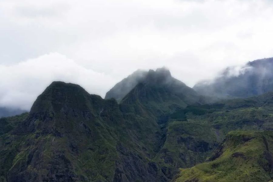Dramatic green mountain peaks covered in low clouds and mist