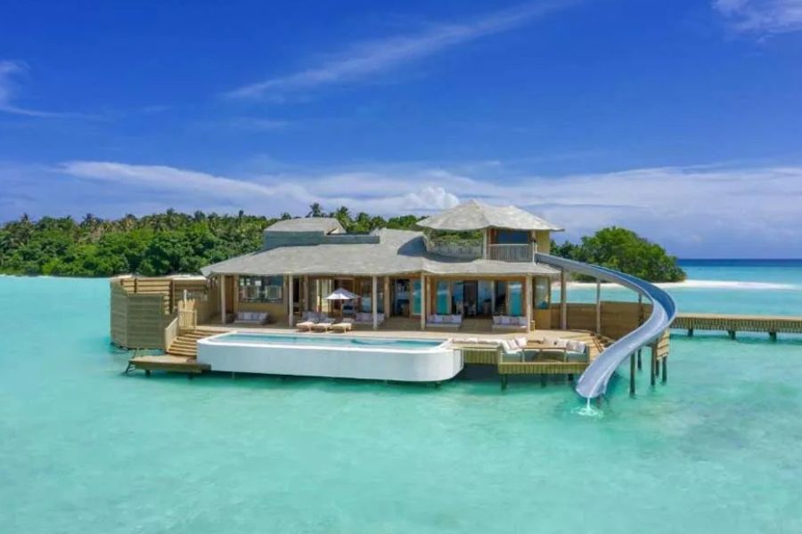 Luxury overwater villa with private pool and water slide into clear turquoise lagoon