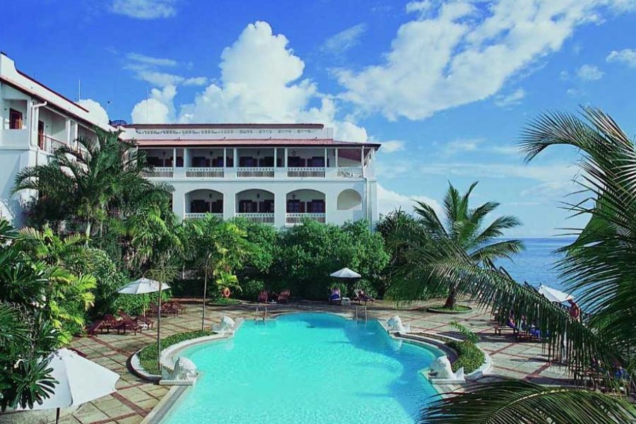 Luxury beachfront hotel swimming pool surrounded by palm trees and ocean views