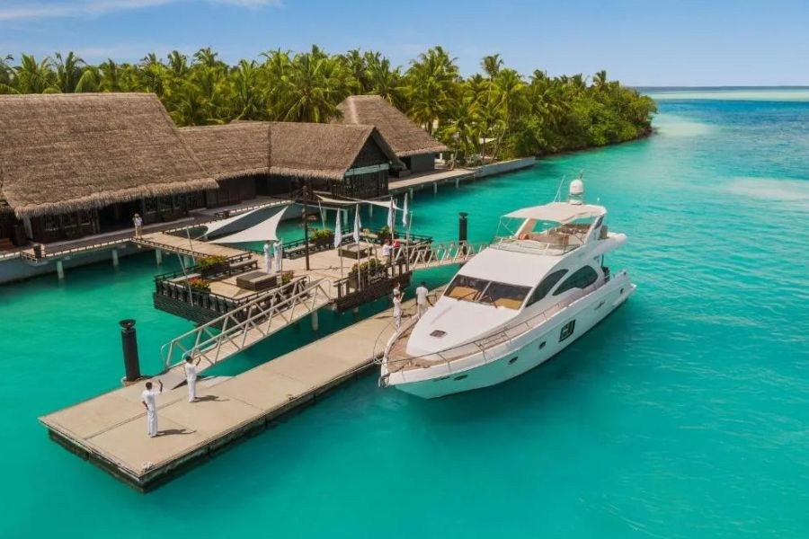 Luxury yacht docked at a tropical island resort pier in clear turquoise water