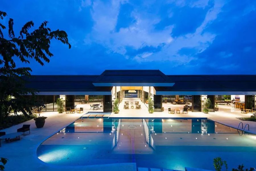 Tropical resort pool with sun loungers, palm trees, and mountain views