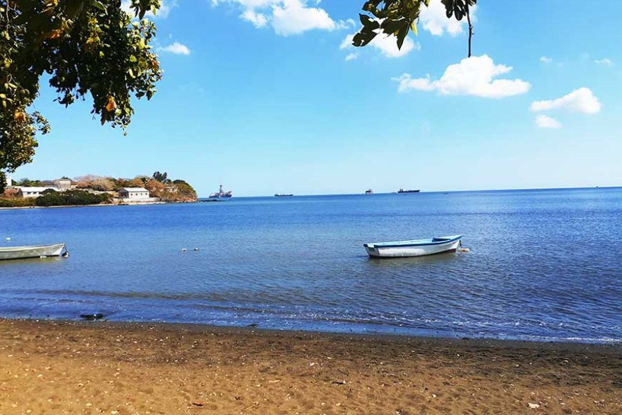 Small fishing boats in a calm bay near Port Louis, Mauritius, with the coastal hillside in the background