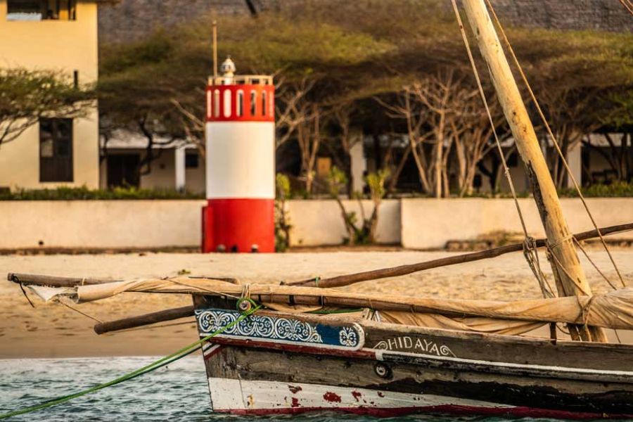 Traditional dhow beside a coastal lighthouse on Kenya’s Indian Ocean shore.
