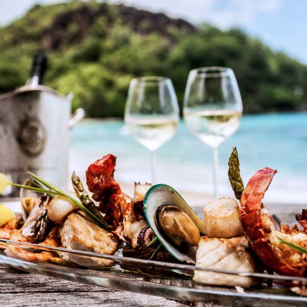 Seafood platter with two glasses of white wine overlooking a tropical beach