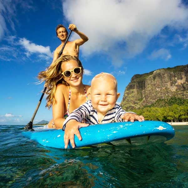 Family paddleboarding together with a coastal mountain in the background