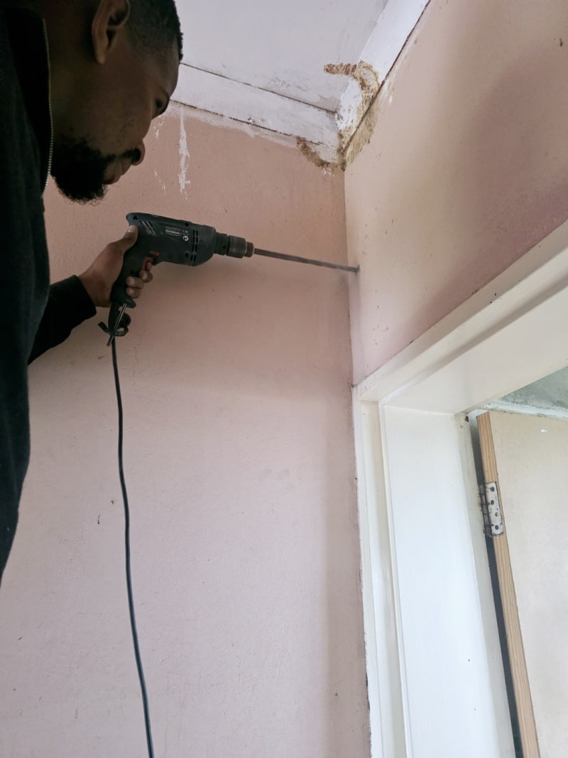 Drilling through the wall to create a secure route for CCTV system cabling.