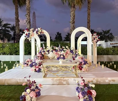 Romantic wedding couple under floral arch setup in outdoor ceremony