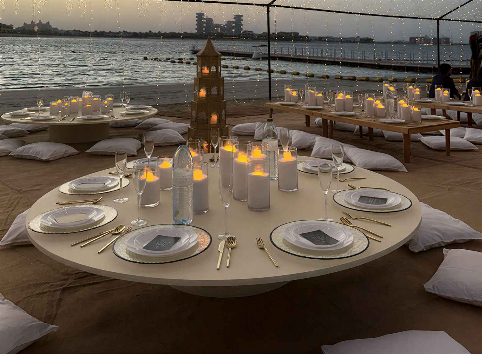 Beachside luxury dining event setup in Dubai with candlelight decor by Aura Events