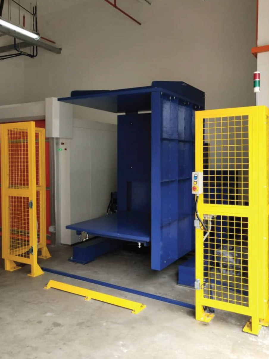 alt with keywords: A pallet changer with prominent safety features like light curtains and an emergency stop button.