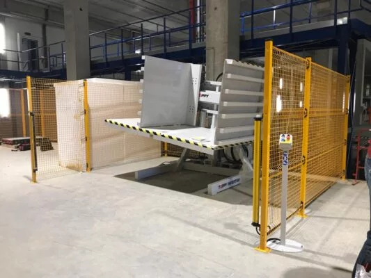A pallet inverter being used in a warehouse for inventory management, with neatly stacked boxes.