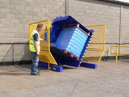 A worker safely operating a pallet inverter with clear controls.