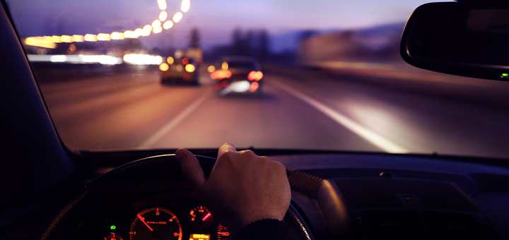 persona manejando de noche por la carretera