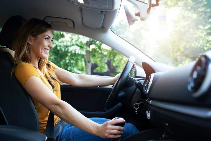 mujer sonriente conduciendo un automóvil