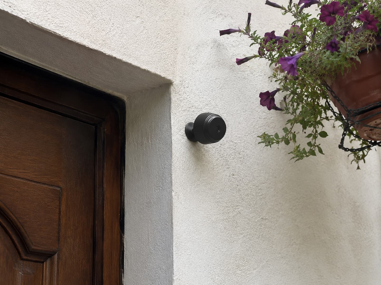 Smartphone in hand showing live camera view of the apartment hallway and door