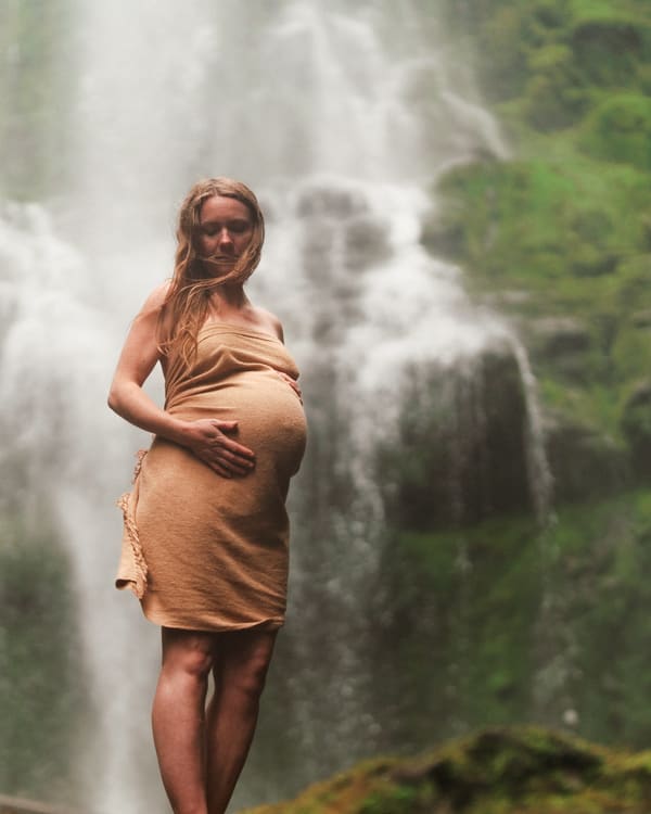 Expecting mother standing near a waterfall during a Wild Play Photography maternity session