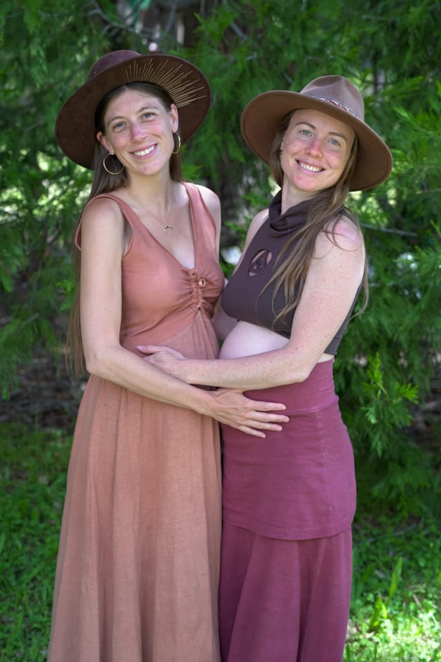 Two women smiling and hugging during a maternity photography session