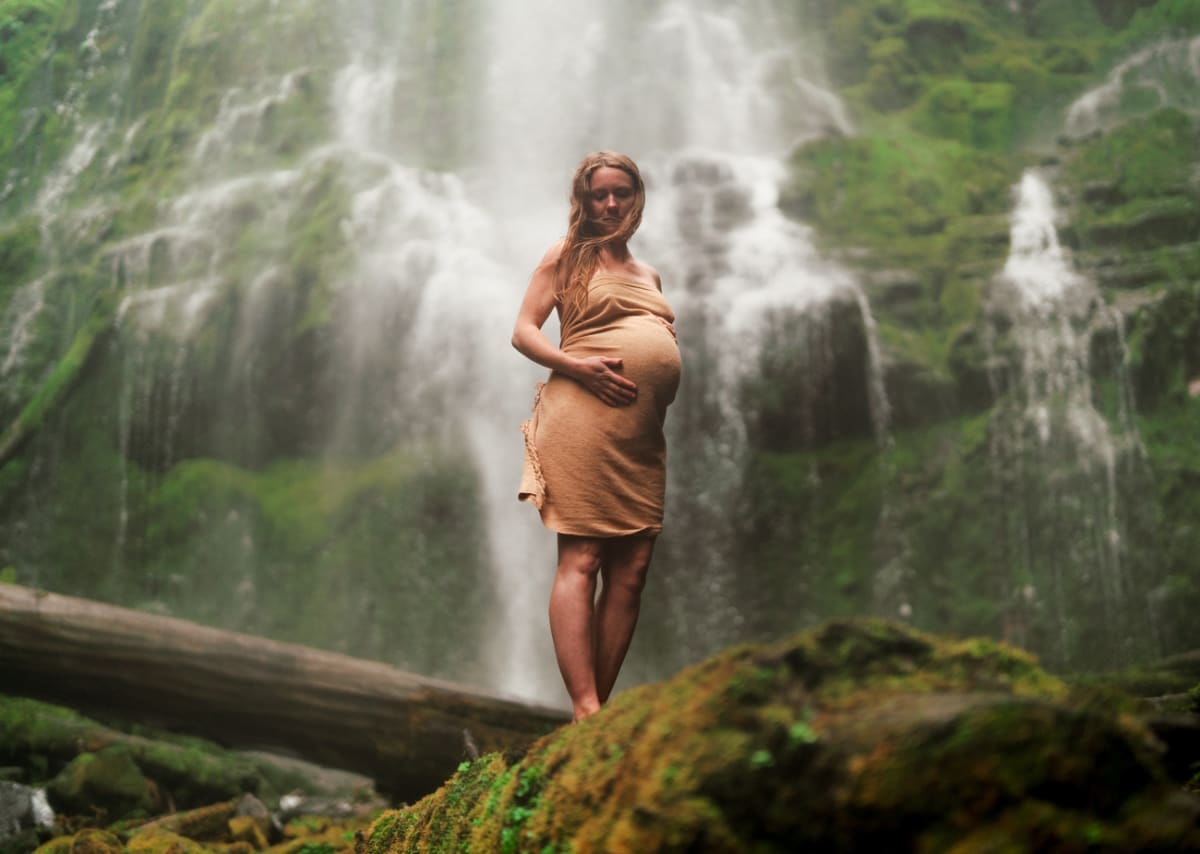 Expectant mother standing near a waterfall
