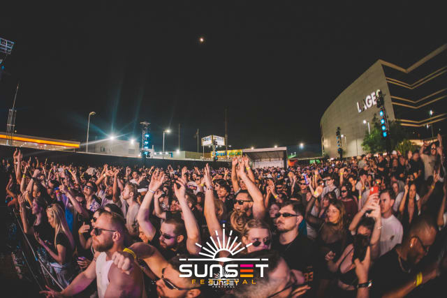Multidão com as mãos para o alto ocupa a pista durante a noite do Sunset Festival 2025.