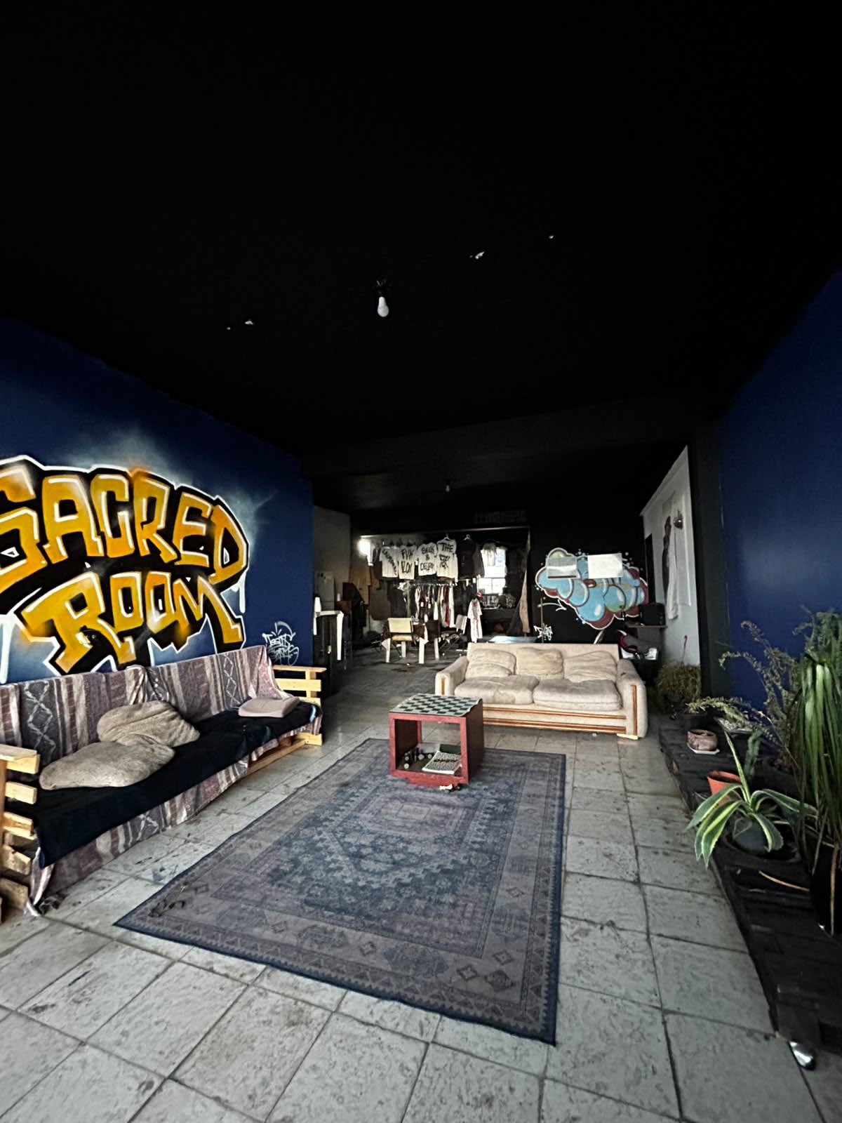 Sala de estar del estudio con el mural de Sacred Room, sillones y plantas