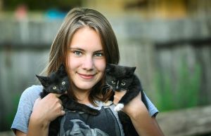 female volunteer smiling while holding two kittens