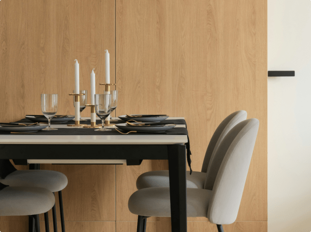 Dining table with four chairs, candles, and tableware.