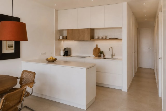 Modern kitchen with white cabinets, a light countertop, and an island with stools.
